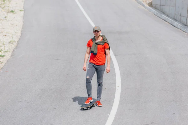 高速タックを実行しながら オープン道路上のロングボードに乗る背の高いフィット男性 — ストック写真