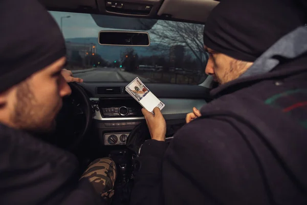 After the successful bank robbery, the thieves are sitting in the car showing off their money and celebrating the win over the law they had.