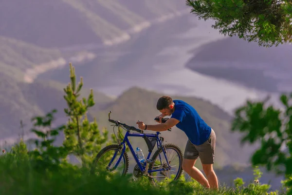 一位疲惫的骑自行车的人一边把自行车推上山坡 一边擦干脸上的汗珠 — 图库照片