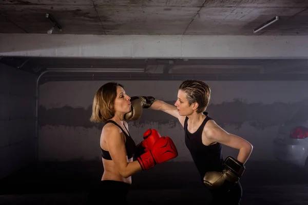 Two professional female boxers punching each other in aggressive garage boxing fight