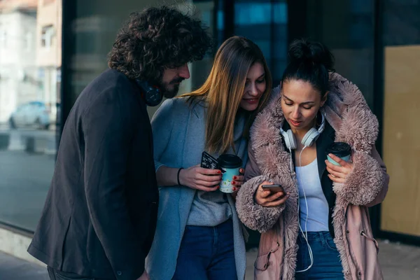 Three Friends Looking Phone While Standing Together Holding Cups Coffee — Stock Photo, Image