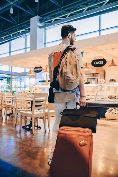 空港ターミナルを歩く旅行スーツケースや荷物を持つ男性旅行者 — ストック写真