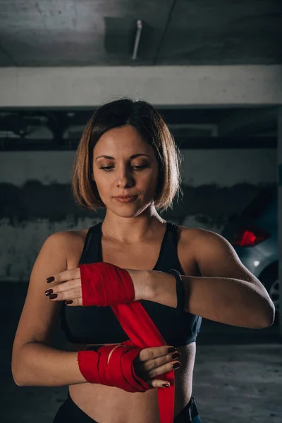 ガレージで赤いボクシング包帯をしている美しい女性のクローズアップポートレート — ストック写真
