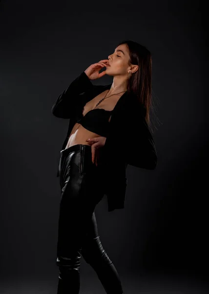 工作室拍摄的一个穿着现代风格裤子和夹克的时髦年轻女子的身体 — 图库照片