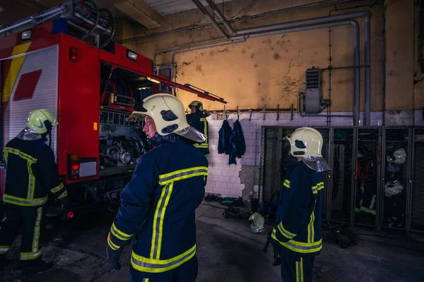 消防队员在消防局内准备制服和消防车 — 图库照片