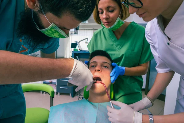 歯医者のチームは歯の道具を使って子供の歯を治療しています — ストック写真
