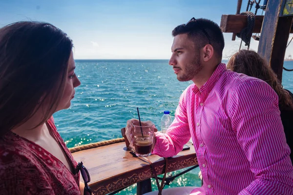 Beautiful couple sitting on the front of a boat on a calm blue sea