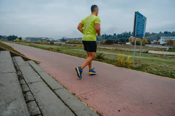 Well built mature runner dressed in fitness wear working out