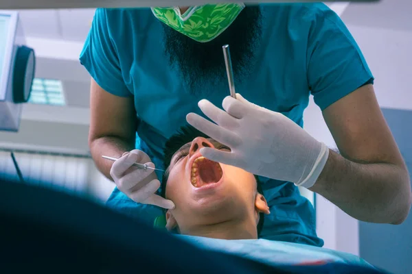 歯医者は歯医者の椅子で10代の少年の歯を調べています — ストック写真