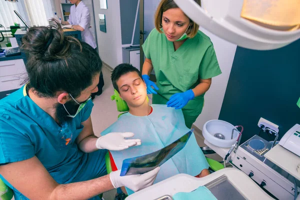 歯のオフィスで彼の歯のX線画像を示す男性と女性の歯科医 — ストック写真