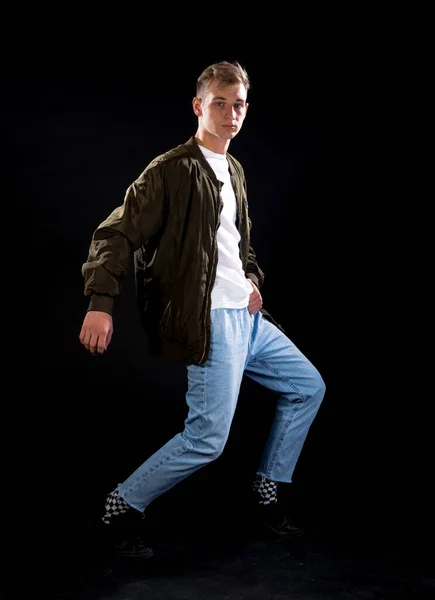 工作室拍摄的一个穿着牛仔裤和绿色运动夹克的时髦年轻人的身体 — 图库照片