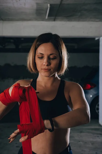 ガレージで赤いボクシング包帯をしている美しい女性のクローズアップポートレート — ストック写真