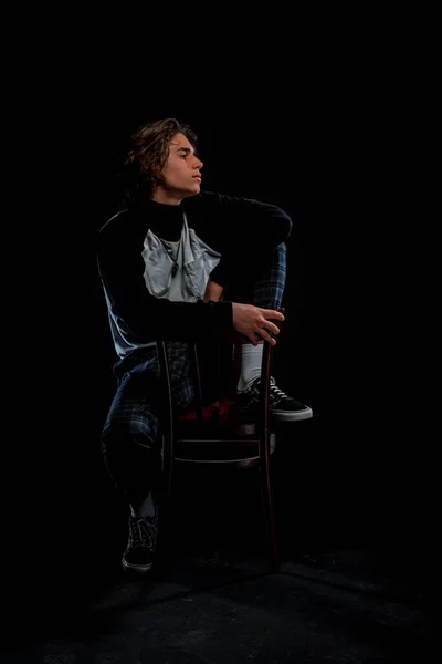 魅力的なスタイリッシュな男の肖像椅子に座って暗い背景に対してポーズ — ストック写真