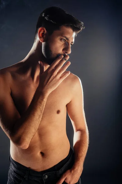 一个穿着黑色裤子抽烟的赤身裸体男人的画像 — 图库照片