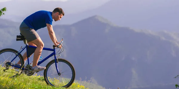 健康的男子自行车手一边骑自行车下山 一边欣赏着令人惊奇的高山土路 — 图库照片