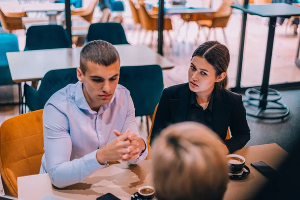 カフェのテーブルでタブレットやコーヒーを飲みながら 美しい若いカップルが彼らの不動産業者と話しているのトップビュー — ストック写真
