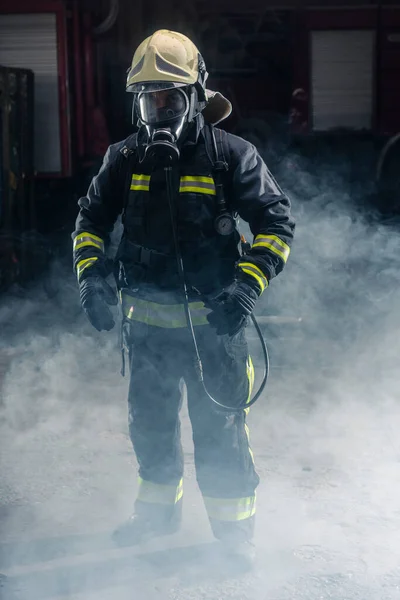 消防士が消防士のターンアウトとヘルメットを着ての肖像画 煙と青の光で暗い背景 — ストック写真
