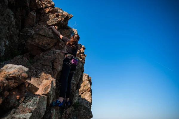 女性の極端な登山家は日の出に対して急な岩を征服する — ストック写真