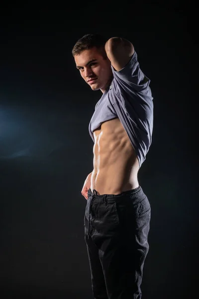 セクシー男性モデルショー彼の腹筋中にスタジオで上の暗い背景 — ストック写真