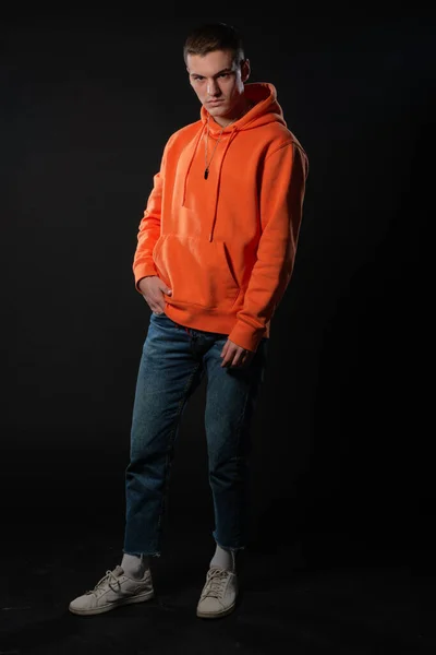 Jonge Knappe Man Jeans Oranje Hoodie Poseren Terwijl Hij Een — Stockfoto