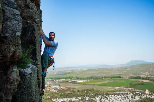 青空の壁を背景に若い男が登る — ストック写真