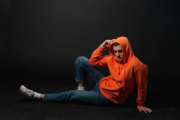 Man Modell Sitter Golvet Och Poserar Orange Sport Hoodie Isolerad — Stockfoto