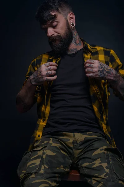 Człowiek Brodą Tatuażami Rękach Szyi Żółtej Czarnej Koszuli Wojskowych Spodniach — Zdjęcie stockowe