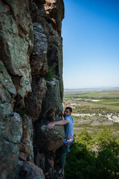 若い大胆不敵な男が山の急な壁に登る — ストック写真