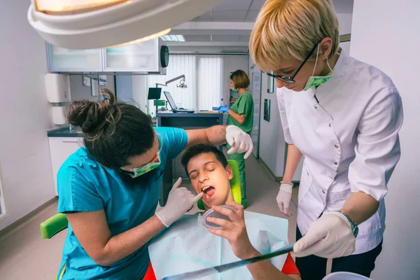 男性歯科医と女性アシスタントショー若い男の子患者彼の歯X線画像で歯科事務所 — ストック写真
