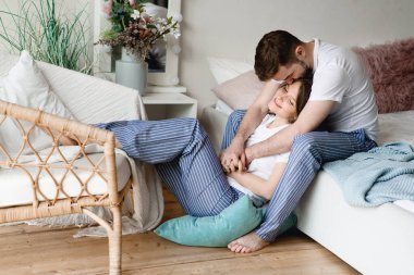 Adam nazikçe yere oturmuş kıza sarılıyor.