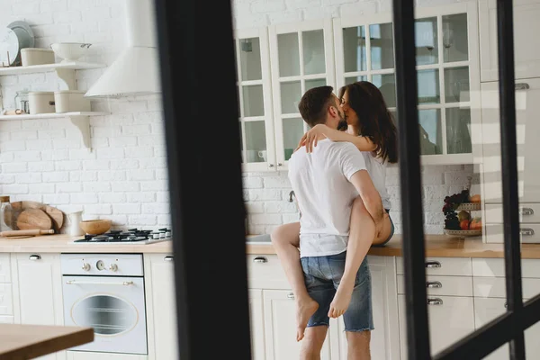 Der Kerl Küsst Leidenschaftlich Das Mädchen Das Auf Dem Küchentisch Stockfoto