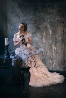 Eski elbiseli ve elinde çiçekle romantik bir kızın portresi.