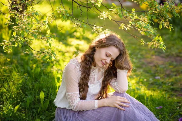Ein Mädchen Mit Langen Zöpfen Sitzt Gedanken Einem Frühlingsgarten — Stockfoto