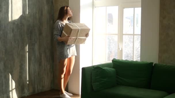 Chica feliz sosteniendo regalos de Navidad y mirando a través de la ventana — Vídeos de Stock