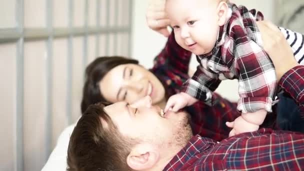Boldog szülők feküdt, és aranyos baba a bedat otthon hálószoba — Stock videók