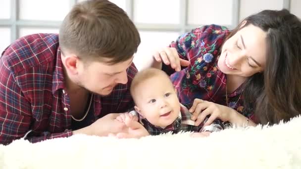 Padres felices acostados con su lindo hijo en la cama en el dormitorio — Vídeos de Stock