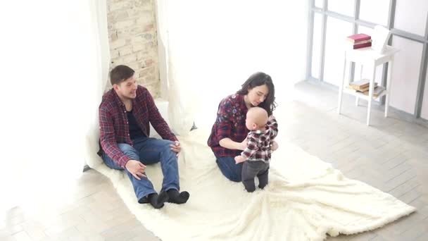 Familia joven sentada en el pasillo en casa y mirando a su hijo — Vídeos de Stock