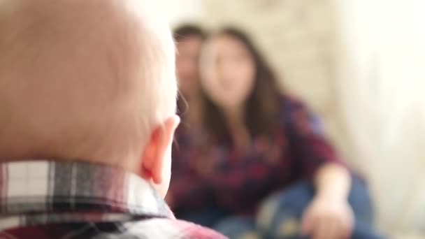 Um bebê bonito se senta no chão e olha para seus pais — Vídeo de Stock