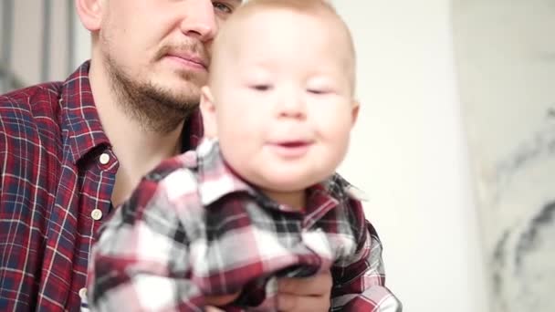 Een jonge vader met een vreugdevolle zoon op zijn knieën — Stockvideo