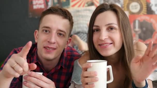 若いカップルがベッド、幸せな笑顔の女性男性恋人愛ロマンチックな朝スローモーションでコーヒーを飲む — ストック動画