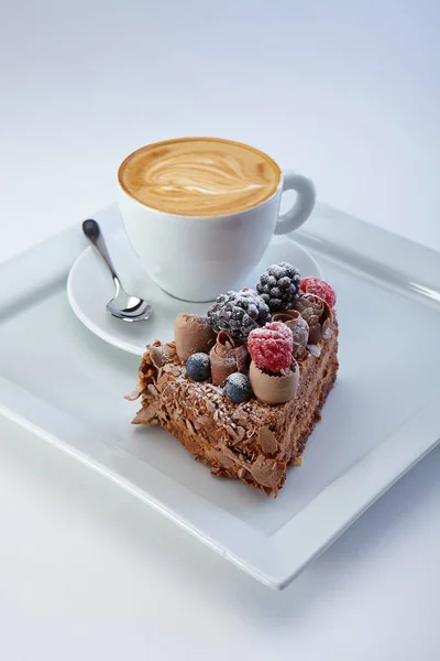 Кусок шоколадного пирога с дикими ягодами подается с чашкой — стоковое фото