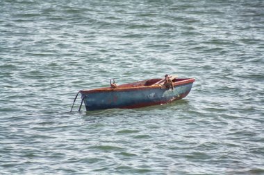 Yalnız, yaşlı bir balıkçı teknesi dalgalarda sallanıyor.