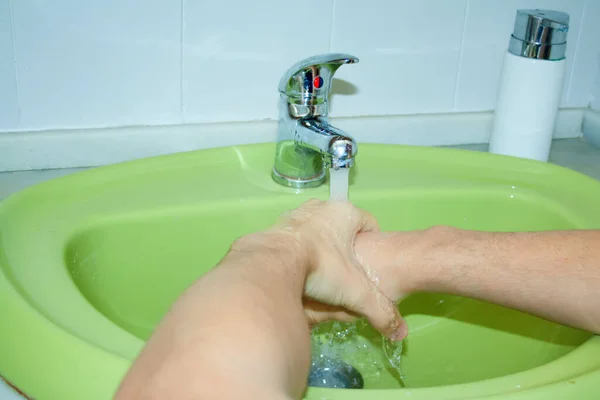 A person washes well-soaped hands under a tap with water.Rules for disinfection.