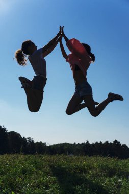 Gün batımında parkta zıplayan arkadaş silueti