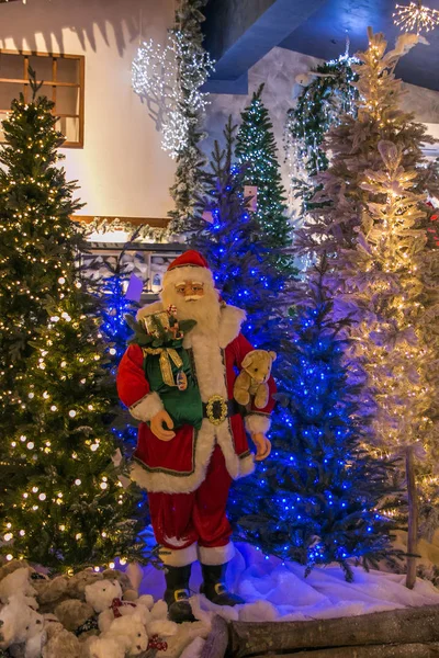 Санта-Клаус возле рождественской елки с огнями — стоковое фото