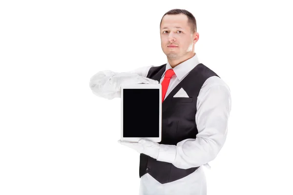 Bonito jovem garçom em luvas e vermelho cravat segurando comprimido — Fotografia de Stock