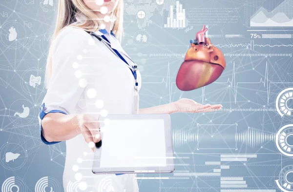 Exposição dupla Médico segurando órgãos humanos (coração) e tablet, fundo cinza . — Fotografia de Stock