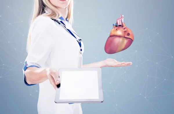 Podwójna ekspozycja lekarz posiadający ludzkie narządy (serce) i tablet, szare tło. — Zdjęcie stockowe