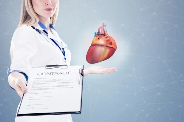Exposição dupla Médico segurando órgãos humanos (coração) e tablet, fundo cinza . — Fotografia de Stock