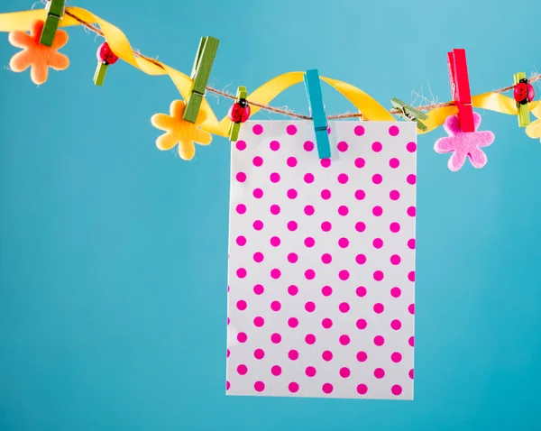 Lege kaart gevestigd op de waslijn. Ruimte voor formuleringen te kopiëren. Vastgemaakt met bloem pinnen. Blauwe, oranje achtergrond. Hoge resolutie foto. — Stockfoto